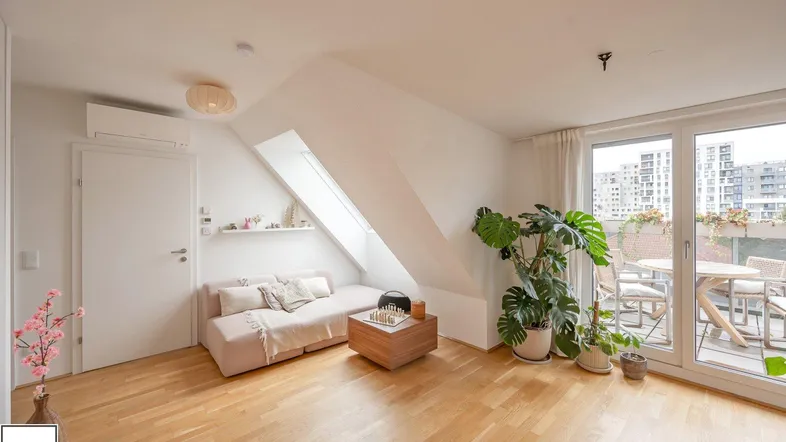 Helles Wohnzimmer mit gemütlichem Sofa, Holzfußboden und Zugang zu einem sonnigen Balkon.