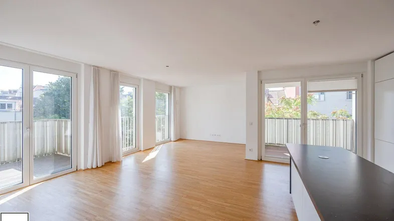Heller, offener Wohnbereich mit Parkettboden, großen Fenstern und Zugang zu mehreren Balkonen.