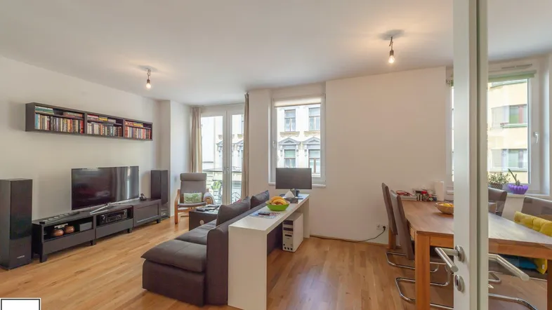 Helles Wohn- und Esszimmer mit Holzboden, Sofa und Esstisch, ideal für geselliges Beisammensein.