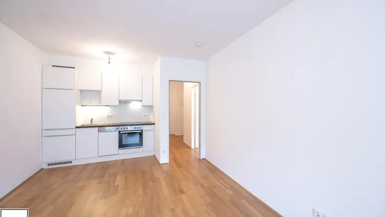 Helle, offene Küche mit weißen Schränken und Holzboden in einem modernen Wohnbereich.