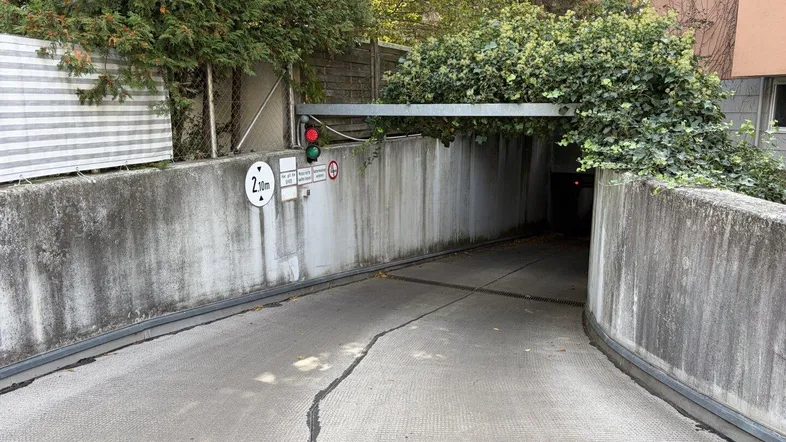 Einfahrt zur Tiefgarage mit Höhenbegrenzung, Ampelsystem und begrüntem Überbau.