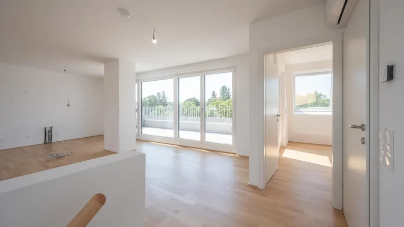 Heller, unmöblierter Wohnbereich mit großen Fenstern und Zugang zu einer Terrasse, ideal für modernes Wohnen.