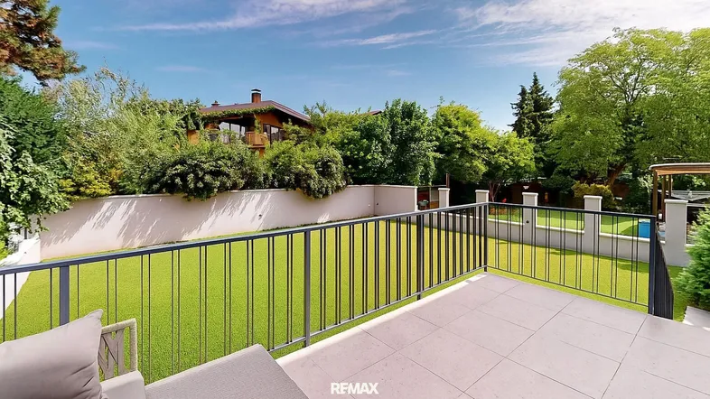 Geräumige Terrasse mit modernen Gartenmöbeln und Blick auf den gepflegten Garten und das Haus.