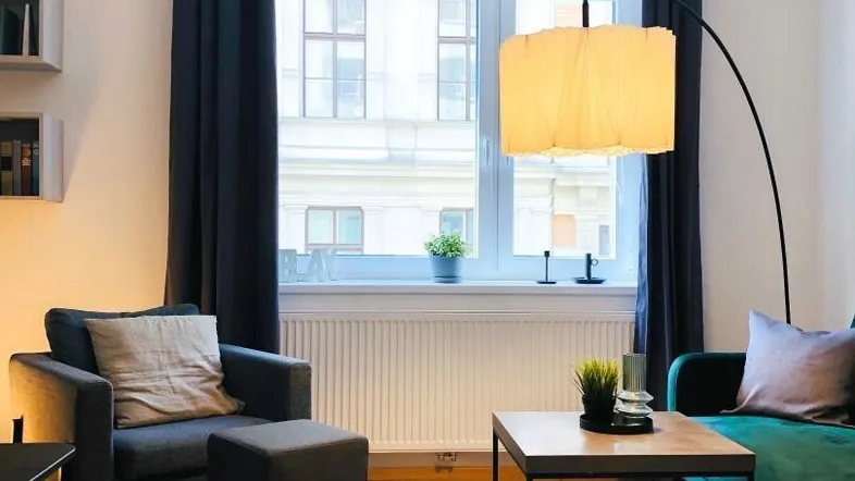 Helles Wohnzimmer mit modernem Sofa, Sessel, Holzboden und großer Bogenlampe.