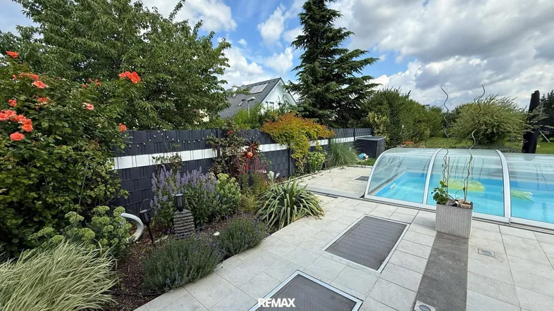 Gepflegter Gartenbereich mit üppiger Bepflanzung, Pool und Sichtschutz zum Nachbargrundstück.