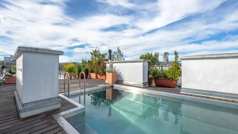 Dachterrasse mit privatem Pool, Holzdeck und Pflanzen unter blauem Himmel.