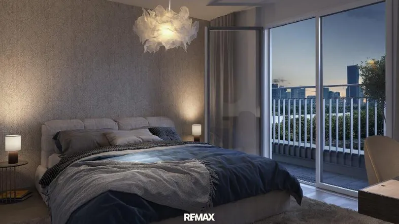 Modernes Schlafzimmer mit großem Bett, Balkonzugang und Blick auf die Stadt bei Dämmerung.