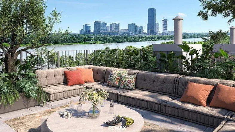 Große Dachterrasse mit bequemen Loungemöbeln, üppiger Bepflanzung und weitem Blick auf die Stadt und den Fluss.