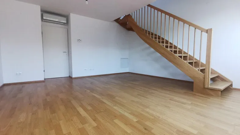 Heller Wohnbereich mit Holztreppe und Parkettboden, ideal für offenes Wohnen auf zwei Ebenen.
