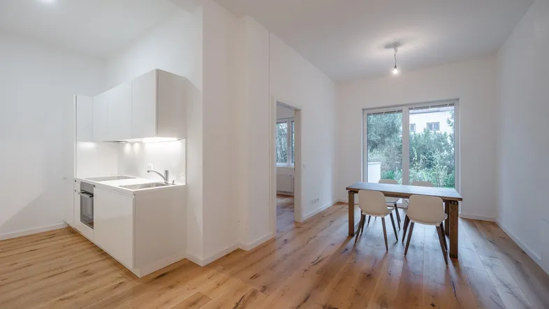 Helle, offene Wohnküche mit moderner Einbauküche, Holzboden und Essbereich mit Blick ins Grüne.