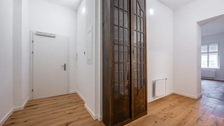Heller Eingangsbereich mit Holzboden und einem eleganten Einbauschrank in dunklem Holz.