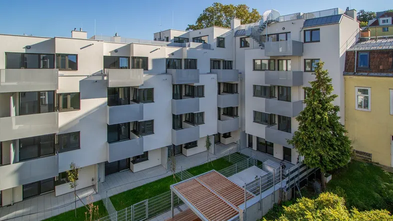 Moderne Wohnanlage mit mehreren Balkonen und einem begrünten Innenhof.