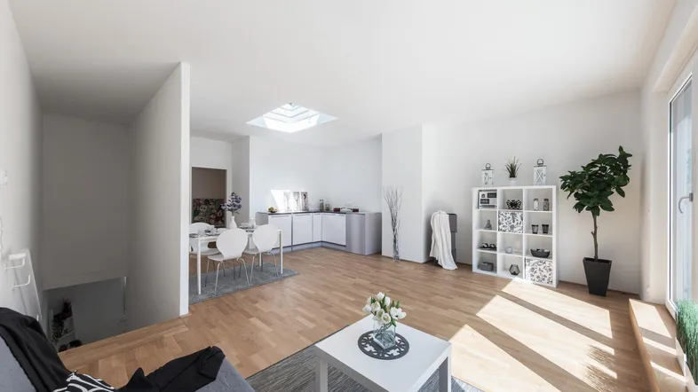 Helles, offenes Wohnzimmer mit Essbereich, kleiner Küche und Holzfußboden.
