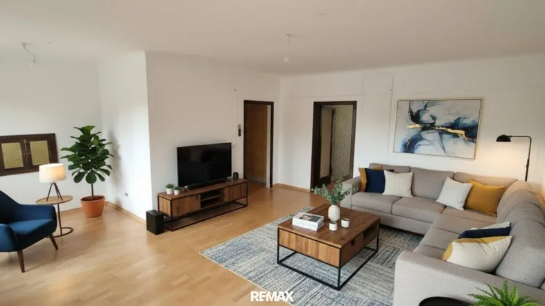 Modern eingerichtetes Wohnzimmer mit Sofa, Fernseher und Holzboden, hell und einladend.