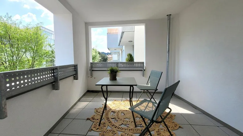 Möblierter Balkon mit Fliesenboden und Blick auf die Umgebung, ideal für entspannte Stunden im Freien.