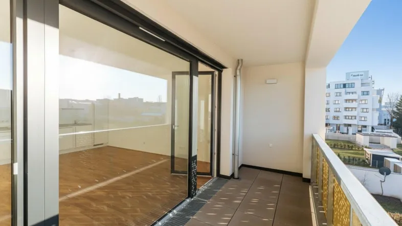 Geräumiger Balkon mit großen Glasschiebetüren und Blick auf die Umgebung.