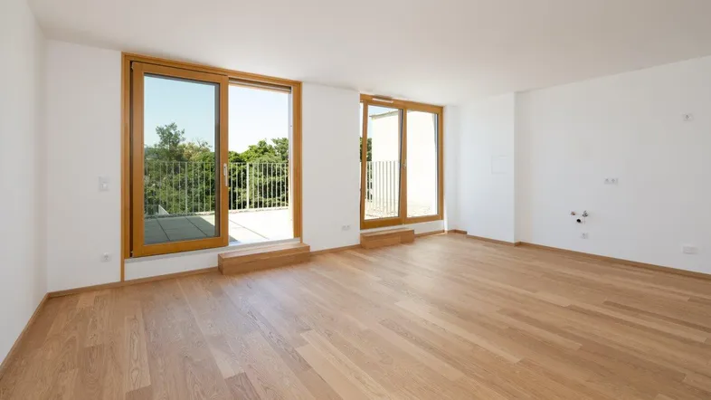 Geräumiges, helles Wohnzimmer mit Holzboden und großen Fenstern zum Außenbereich.