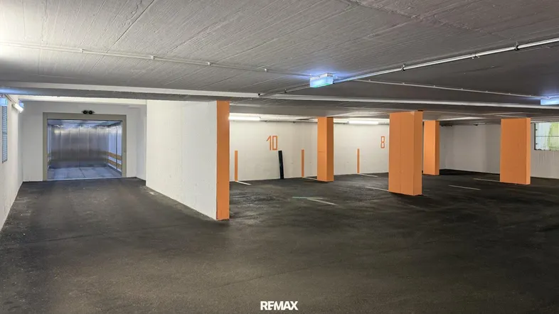 Tiefgarage mit nummerierten Stellplätzen und Zugang zum Aufzug, gut beleuchtet und geräumig.