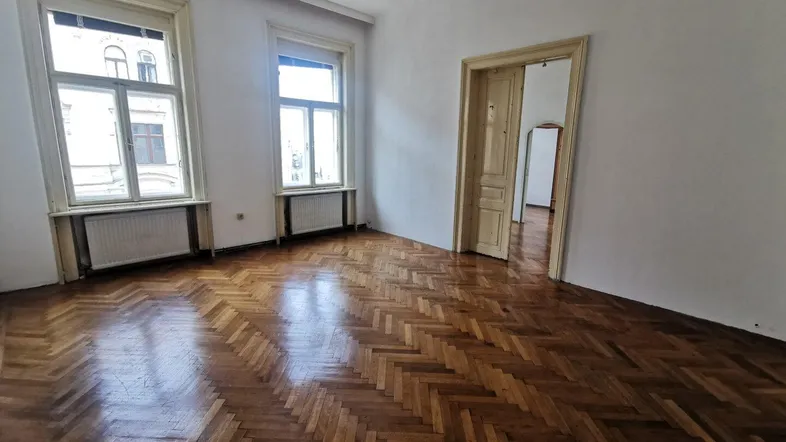 Helles Zimmer mit Fischgrätparkettboden und zwei großen Fenstern, ideal als Wohn- oder Schlafzimmer.