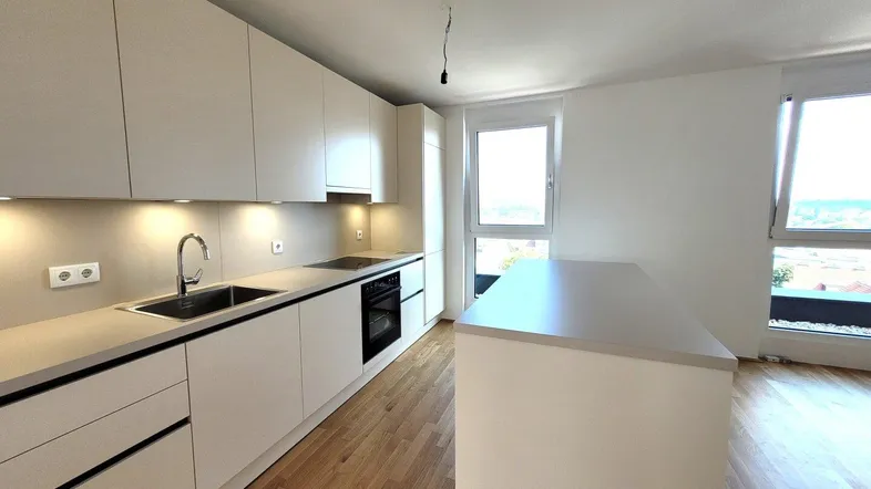 Moderne Küche mit hellen Schränken, Holzboden und einer Kücheninsel, die viel Arbeitsfläche bietet.