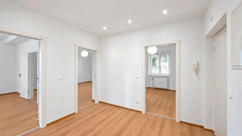 Heller Flur mit Laminatboden und Zugang zu mehreren Zimmern der Wohnung.