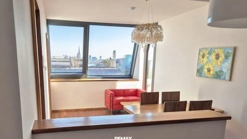 Heller Wohn- und Essbereich mit Holzboden, modernen Möbeln und Stadtblick durch große Fenster.