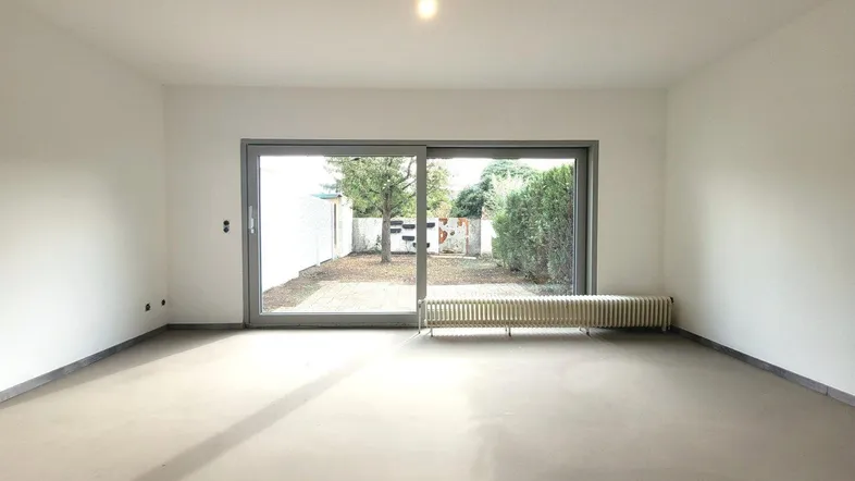 Helles Wohnzimmer mit großem Schiebefenster und direktem Zugang zum Gartenbereich.