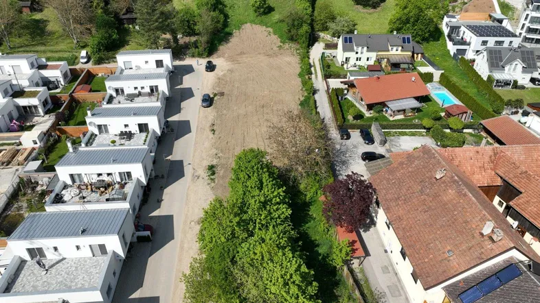 Luftaufnahme eines Baugrundstücks umgeben von modernen Neubauten und grüner Landschaft.