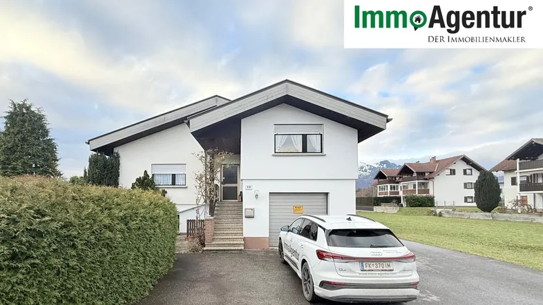 Ansicht des Einfamilienhauses mit Garage, Einfahrt und gepflegter Hecke im Vordergrund.