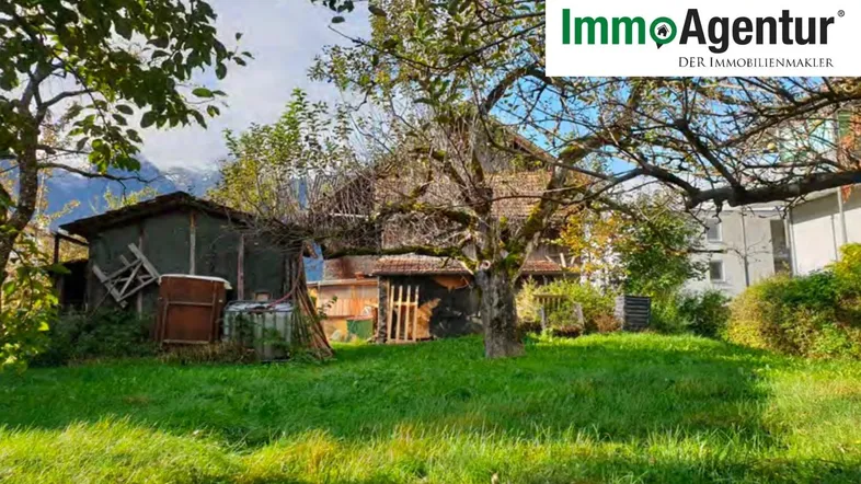 Großer Gartenbereich mit Rasenfläche, alten Bäumen und Blick auf die Berge im Hintergrund.