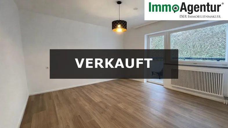 Helles Wohnzimmer mit Laminatboden, weißen Wänden und Zugang zu einem kleinen Balkon.