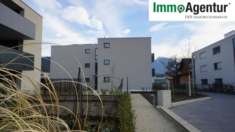 Moderne Wohngebäude in einer ruhigen Umgebung mit Blick auf die Berge unter blauem Himmel.