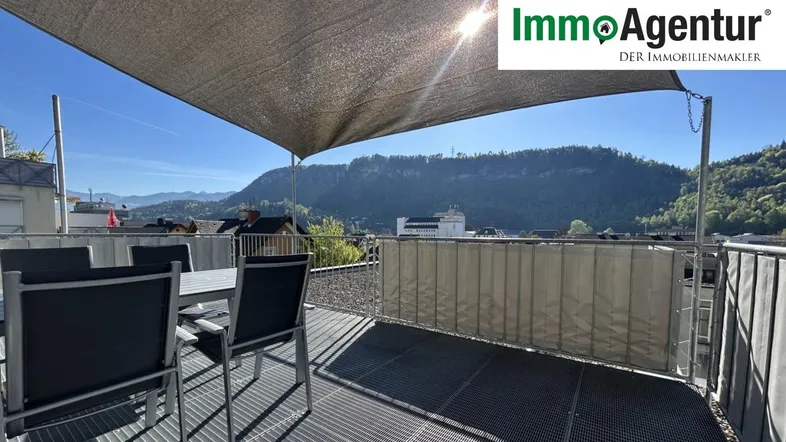 Sonnige Dachterrasse mit Esstisch, Sonnensegel und weitem Blick auf die umliegende Berglandschaft.