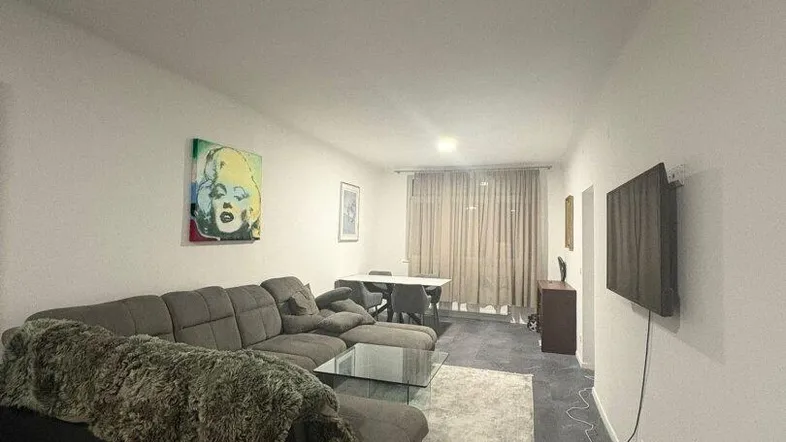 Geräumiger Wohn- und Essbereich mit modernem Sofa, dunklen Fliesen und Kunst an der Wand.