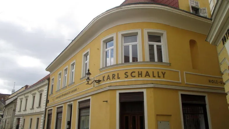 Gelbes Eckgebäude mit traditioneller Architektur und Geschäftsfassade an einer Straße.