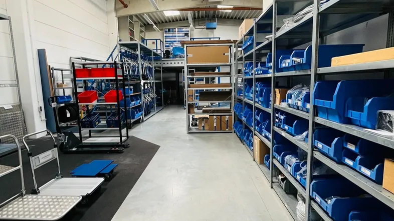 Geräumiger Lagerbereich mit hohen Decken, Metallregalen und blauen Lagerbehältern für effiziente Organisation.