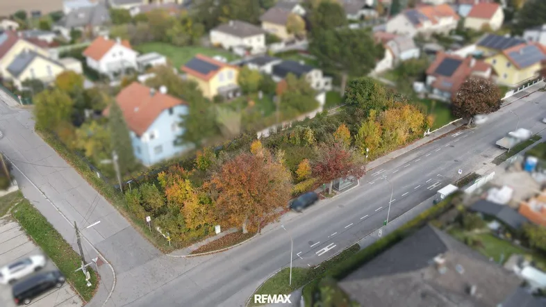 Luftaufnahme eines Grundstücks in einer Wohngegend mit herbstlichen Bäumen und umliegenden Häusern mit Solaranlagen.