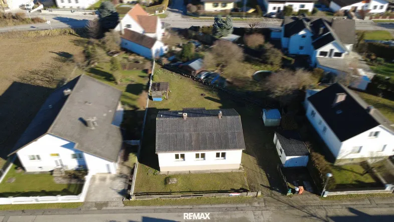 Luftaufnahme des Einfamilienhauses mit umliegendem Garten und Nachbarschaft in ländlicher Umgebung.