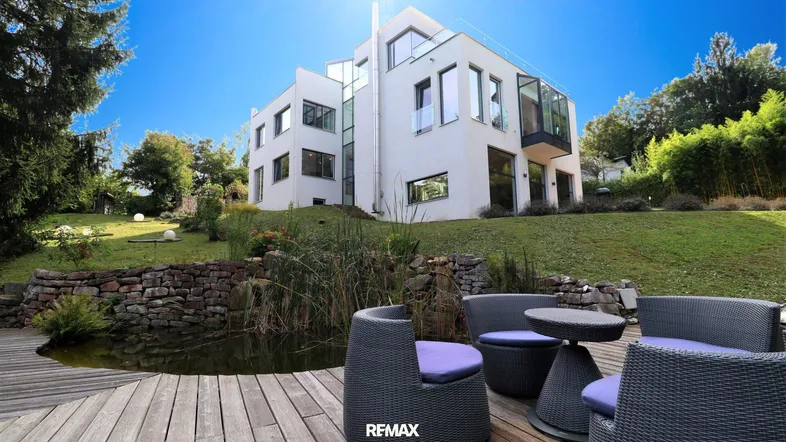 Moderne Villa mit weitläufigem Garten, Teich und Holzterrasse für entspannte Stunden im Freien.