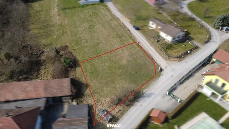 Luftaufnahme eines Baugrundstücks, rot umrandet, mit umliegenden Häusern und Straßen.