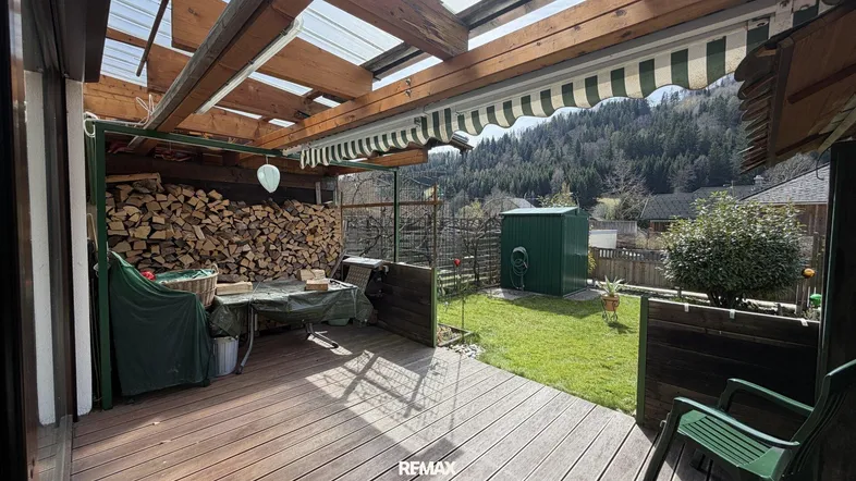Überdachte Holzterrasse mit Bergblick und Lagerplatz für Brennholz.