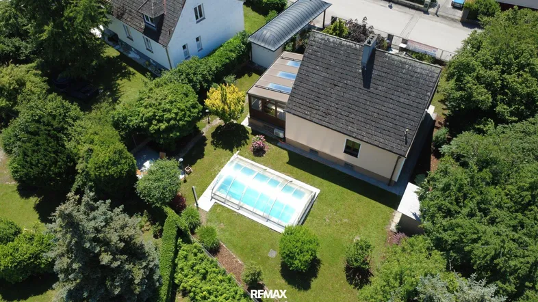 Luftaufnahme des Hauses mit großem Garten, Pool und umgebender Grünfläche.