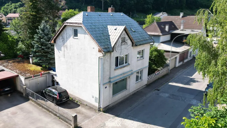 Luftaufnahme eines freistehenden Hauses mit Satteldach, Garage und angrenzender Straße.