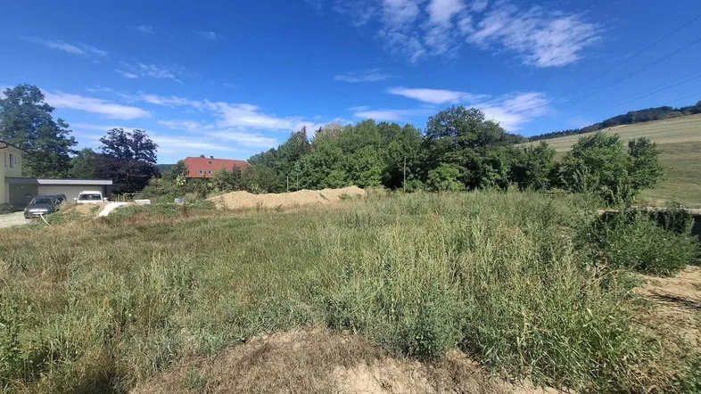 Grünfläche mit Baulandpotenzial und Blick auf die ländliche Umgebung unter blauem Himmel.