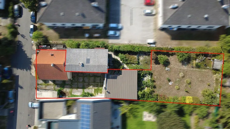 Luftaufnahme des Grundstücks mit Wohnhaus, gepflastertem Bereich und großem Garten.