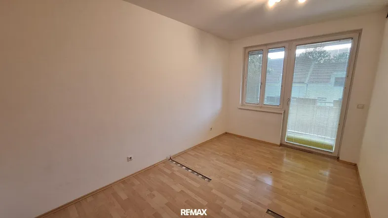 Leerer Raum mit Holzboden und Zugang zu einem Außenbereich, bereit zur Gestaltung.