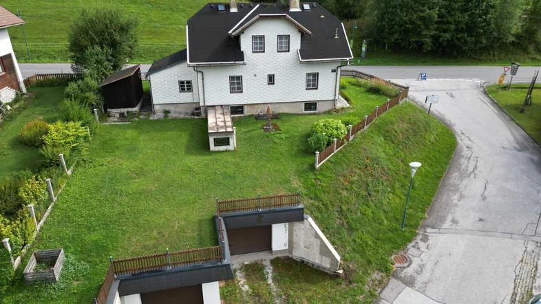 Luftaufnahme des Hauses mit großem Garten, Zufahrt und zwei Garagen.