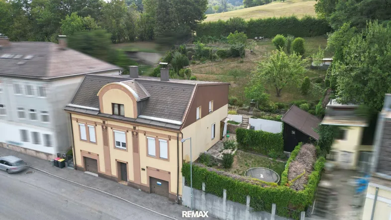 Luftaufnahme eines Hauses mit Garten, umgeben von viel Grün und einer ruhigen Wohngegend.