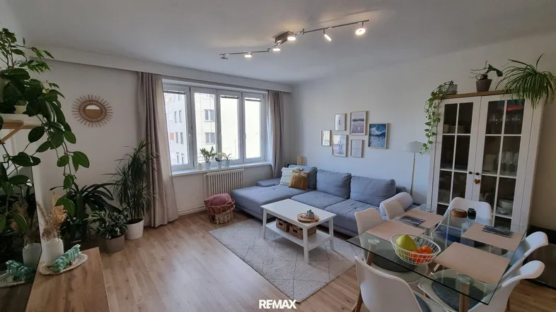 Helles Wohn- und Esszimmer mit Parkettboden, bequemer Couch und Esstisch für gesellige Stunden.