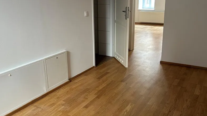 Helles Zimmer mit Parkettboden und Zugang zu weiteren Räumen, ideal für eine flexible Nutzung.
